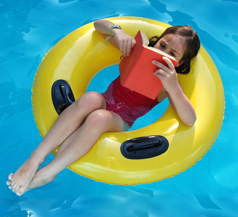Nine year old girl reading on a yellow lifesaver.