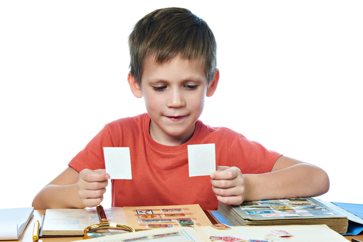 A little boy is seen holding two cards. 